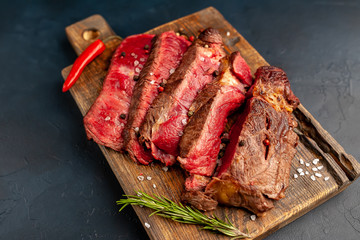 Grilled rib eye beef steak with herbs and spices on a stone background