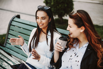 Beautiful young brunette explaining something gesticulating to her girlfriend while another one is...