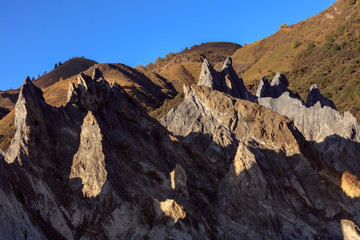Fototapeta premium Bamei stone forest, exotic pillars of gray stone situated in the grasslands of Sichuan Province, China. Unique rock formations with clouds in the distant background. Martian Tibetan Landscape