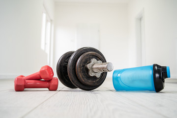 Dumbbell, and supplement shaker on the floor at home training strength and condition