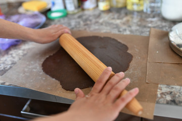 Mom rolls the dough. chocolate dough. Hands work with cake dough recipe preparation. Women's hands, Women's hands roll out the dough. Mom rolls dough on a kitchen board with a rolling pin