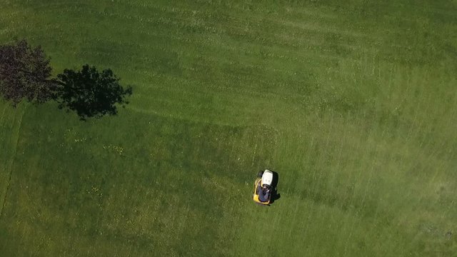 Aerial of a man mowing the grass on a small tractor