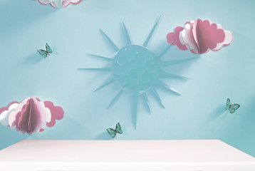 Empty table and the decoration of the wall in the nursery with paper clouds, sun and butterflies