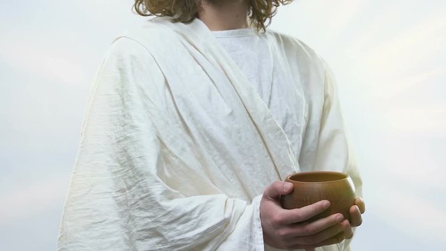 Saint man in white robe holding glass with holy anointing oil, confirmation