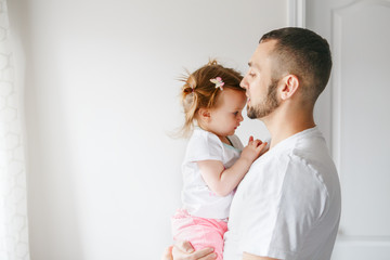 Caucasian father talking speaking with toddler baby girl. Male man parent holding embracing child. Authentic lifestyle touching tender moment. Single dad family life concept. Happy fatherhood