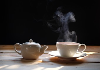 hot tea cup on wood table, Hot drink . with steam,warm soft light, dark background.Good morning Tea or Have a happy day message concept.