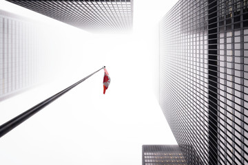 Looking up the Toronto financial district in city downtown with misty sky with flag of Canada