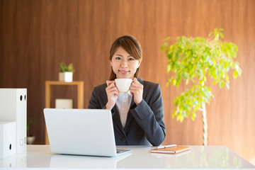コーヒーカップを持ち微笑むビジネスウーマン