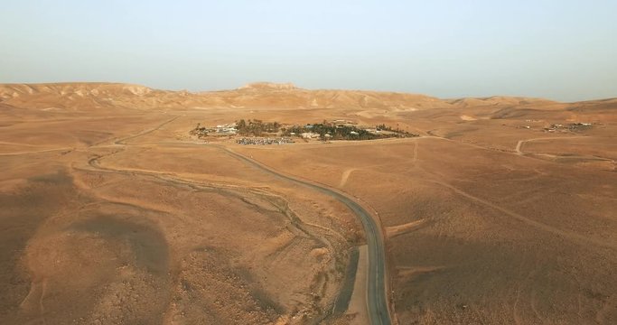 Aerial view of a green oasis of trees, farm fields at the edge of the desert with Mountains around