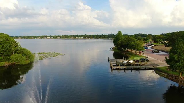 Pan over a beautiful Central Florida Lake with docks and a fountain on a Spring Evening
