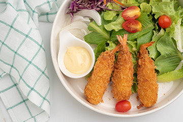 Close up crisp deep-fried prawns with salad in white bowl