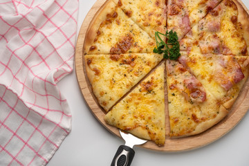 Close up melting cheesy pieces of home made pizza on wooden plate