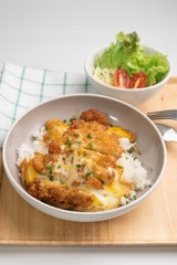 Close up rice bowl topped with deep-fried pork cutlet and eggs decorated with salad in Japanese style