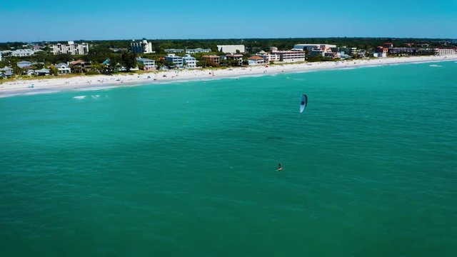 Aerial of man on hydrofoil kitesurfing along Indian Rocks beach shore in Florida.