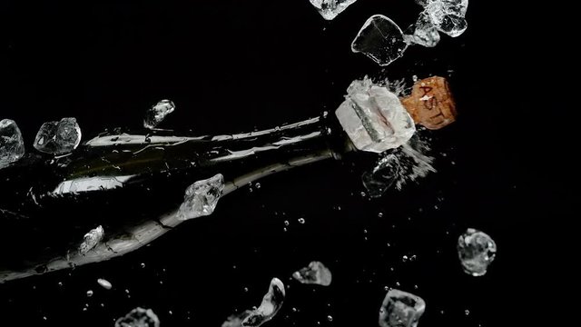 Champagne Bottle Popping out of Ice Cubes Bucket and Exploding with Stream of Sparkling Wine on the Black Background. Shot with High Speed Camera, Phantom Flex 4K.