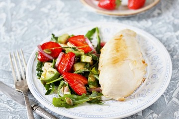 food without carbohydrates - fried chicken breast and salad with strawberries, cheese, avocados, onions and herbs, dressed with oil and balsamic. keto diet. rich in proteins. lunch for keto.