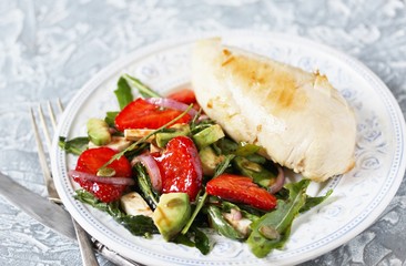 food without carbohydrates - fried chicken breast and salad with strawberries, cheese, avocados, onions and herbs, dressed with oil and balsamic. keto diet. rich in proteins. lunch for keto.
