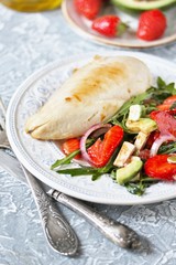 food without carbohydrates - fried chicken breast and salad with strawberries, cheese, avocados, onions and herbs, dressed with oil and balsamic. keto diet. rich in proteins. lunch for keto.