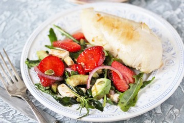 food without carbohydrates - fried chicken breast and salad with strawberries, cheese, avocados, onions and herbs, dressed with oil and balsamic. keto diet. rich in proteins. lunch for keto.