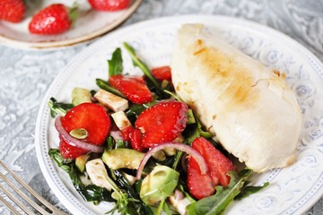 food without carbohydrates - fried chicken breast and salad with strawberries, cheese, avocados, onions and herbs, dressed with oil and balsamic. keto diet. rich in proteins. lunch for keto.