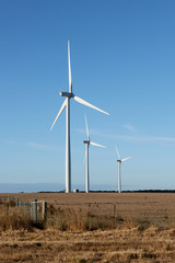 Three wind turbines on a farm in the Australian countryside.