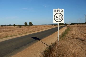 End of speed restriction road sign on a narrow Australian country road signifying an end to a 60...