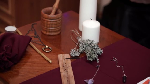 Composition of esoteric objects used for healing, meditation and purifying. Candle, ritual knife, runes and tarot cards on table. Divination, wicca and occult concept. Translate: Emperor, death, devil