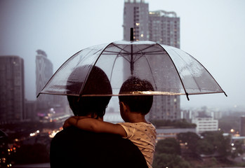 The dad carried the baby and the umbrella during the rainy season in the country.
