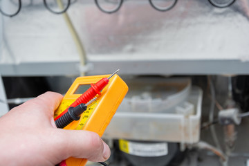  Male Technician Checking Fridge With Digital Multimeter.  Repairman contractor repairing fridge...