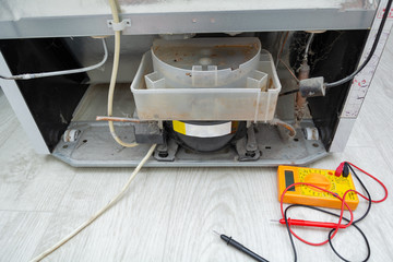  Male Technician Checking Fridge With Digital Multimeter.  Repairman contractor repairing fridge...