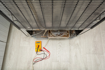  Male Technician Checking Fridge With Digital Multimeter.  Repairman contractor repairing fridge...