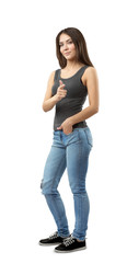 Young woman in sleeveless top and jeans standing in half-turn with left hand in pocket and right hand pointing at viewer isolated on white background.