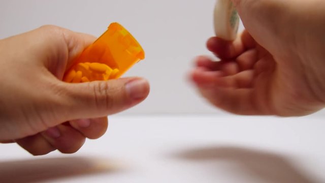Pills pour out onto addict's hand.
