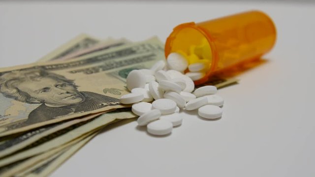 White pills poured out onto stacks of money.