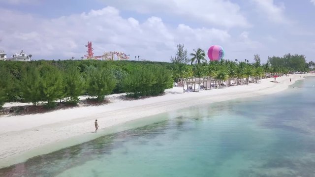 Aerial Shot from Left to Right of a Hot Girl Walking on a Beach with Blue Water and Palm Trees in Bahamas