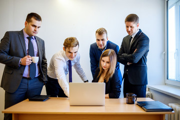 Woman sitting at the desk, the team is standing around her.