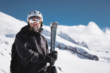 Portrait athlete skier in helmet and ski mask against the snow-capped mountains of a ski resort...