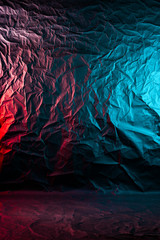 Texture of crumpled black paper. Close up black background of crumpled cardboard under color red and blue studio light
