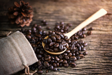 Coffee bean in spoon and bag on wood background