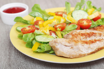 Grilled chicken breast with raw vegetables salad