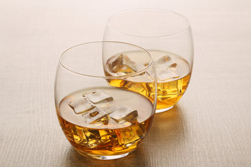 Two glasses with whiskey with ice cubes	