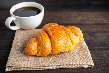 croissants and coffee on old wooden table.