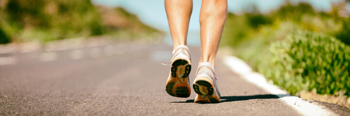 Fit run runner man jogging feet closeup running shoes banner panorama. Athletes legs walking on street for summer marathon.