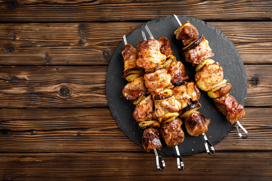 Grilled meat skewers, shish kebab on wooden background, top view