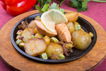 Fried salmon with potatoes on a sizzler