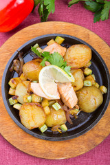 Fried salmon with potatoes on a sizzler