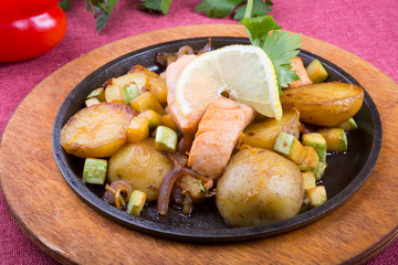 Fried salmon with potatoes on a sizzler