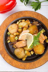 Fried salmon with potatoes on a sizzler