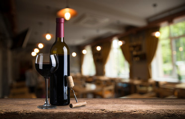 Red wine tasting in the wine cellar: wineglass and bottles next to the window and panoramic view of...