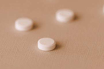 White tablets scattered on a surface close up. Brown color toned